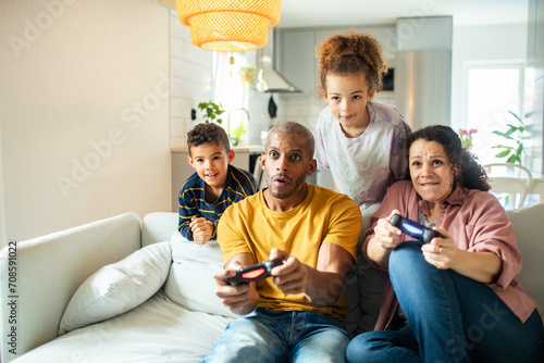 Young parents playing video games with children watching at home photo