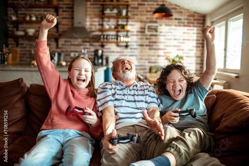 Happy grandfather playing video games with grandchildren at home photo