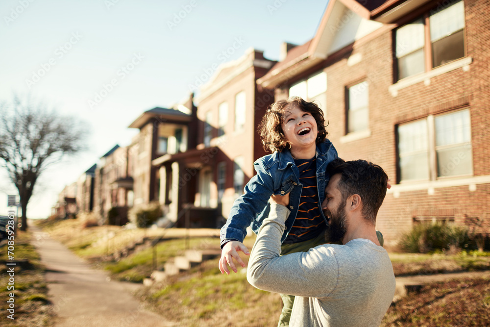 Fototapeta premium Happy child playing with father in sunny suburban street