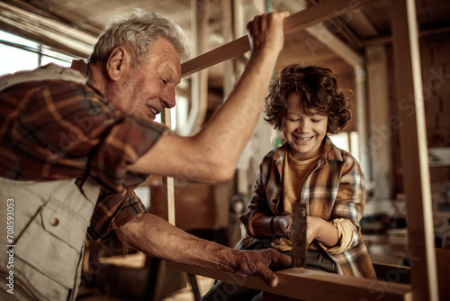 Grandfather and grandson enjoying carpentry work in a home workshop