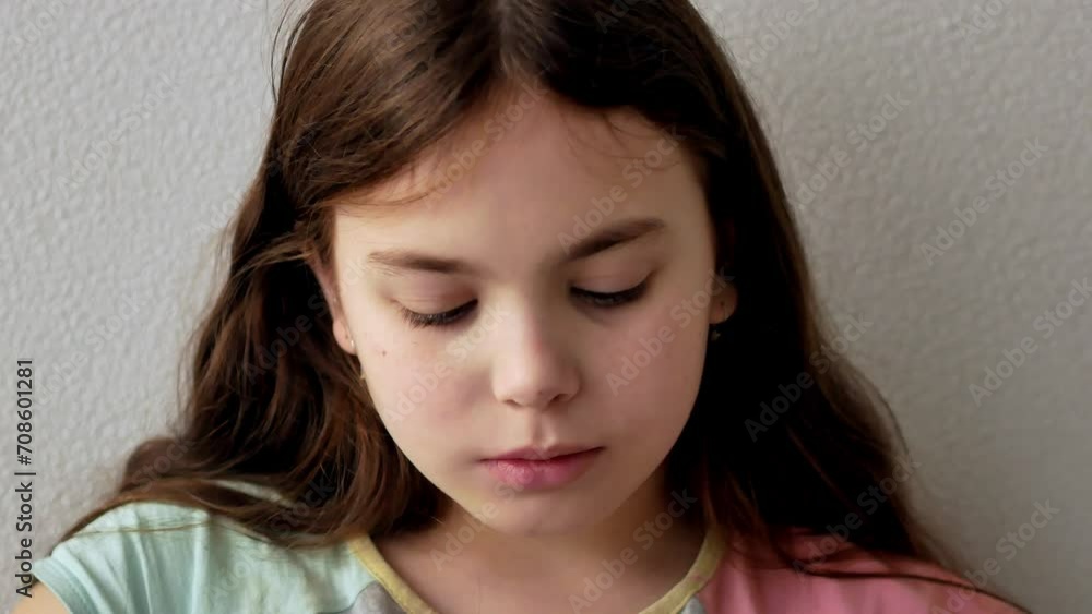 Portrait of a 9-year-old little girl wiping her lips, straightening her disheveled hair in the morning, sitting in bed looking into the frame. Green eyes are lowered down, looking into the frame. Portrait of a 9-year-old little girl wiping her lips, straightening her disheveled hair in the morning, sitting in bed looking into the frame. Green eyes are lowered down, looking into the frame.