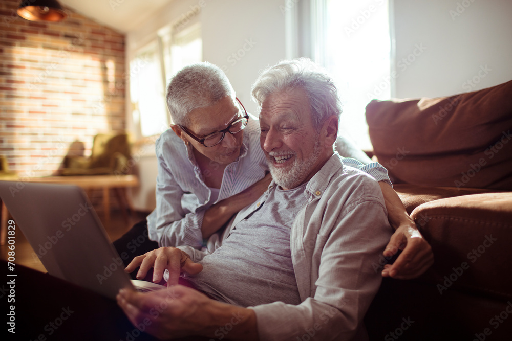 Smiling elderly couple using laptop at home Smiling elderly couple using laptop at home