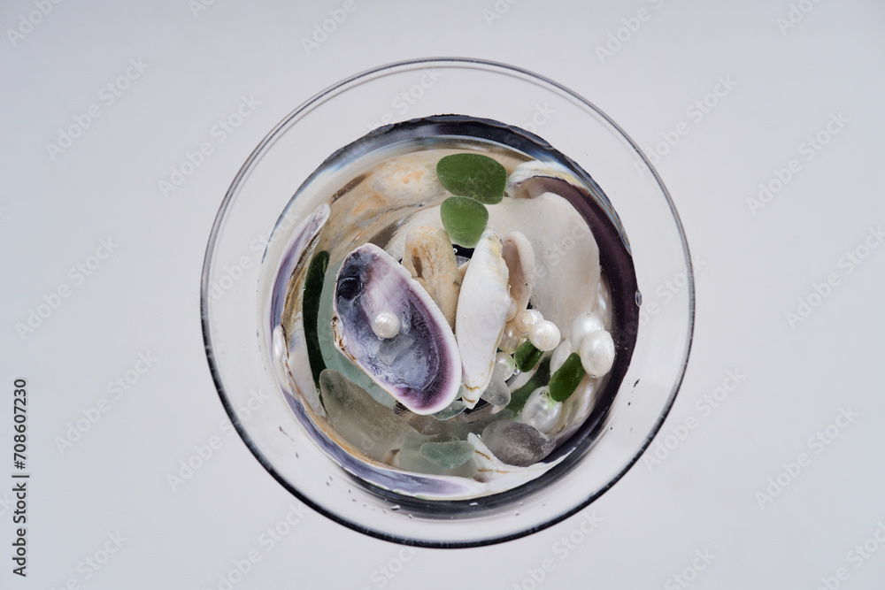 seashells, sea stones, freshwater pearls in a glass glass with water. macro photography seashells, sea stones, freshwater pearls in a glass glass with water. macro photography