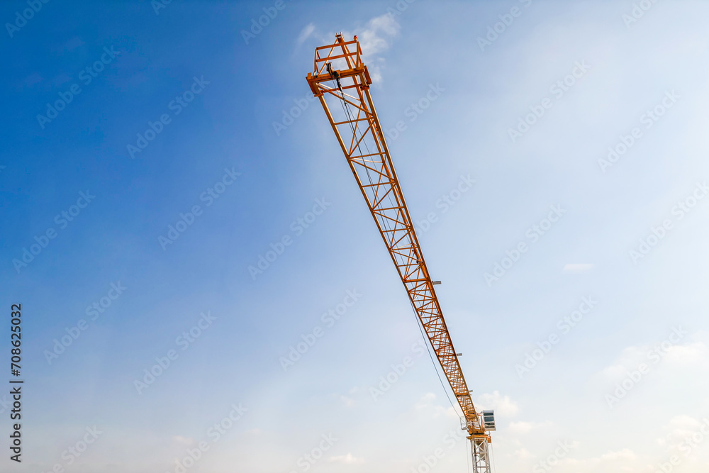 Industrial construction crane with blue sky background at building site Industrial construction crane with blue sky background at building site