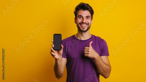 Full body young happy man wears purple t-shirt casual clothes big huge blank screen mobile cell phone smartphone with area point index finger up isolated on plain yellow background. Lifestyle concept. photo