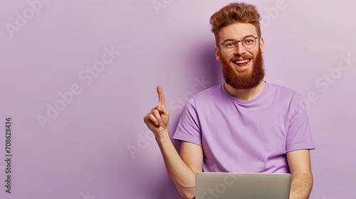 Full body young redhead bearded man in violet t-shirt casual clothes sitting hold use work on laptop pc computer point aside isolated on plain pastel light purple background studio Lifestyle concept