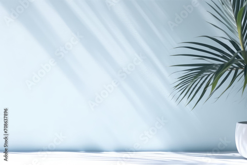 Minimalistic light background with blurred shadow of foliage on light blue wall.