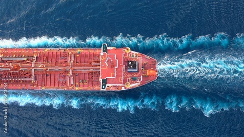 Top-down view of a crude oil tanker speeding through calm waters with trails of foam around her. Powerful diesel engine of the oil tanker roars at full speed and leaves wake water on the Ocean
