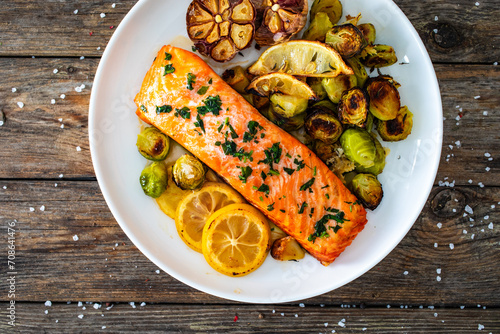 Fried salmon steak and garlic, brussels sprouts and lemon served on wooden table photo