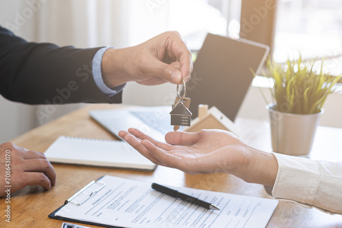Close up agent giving a key to new owner or tenant, client after signed signature contract rental purchase, buyer apartment, home with landlord, realtor. Banker agreement mortgage loan. Property lease photo