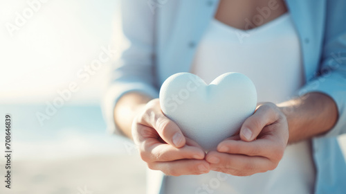 Woman holding a white heart-shaped object with care and tenderness in her hands
