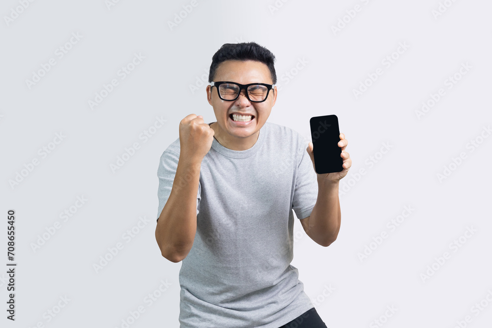 Portrait of excited man show fist up about successful while showing screen smartphone Portrait of excited man show fist up about successful while showing screen smartphone