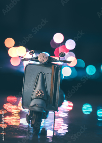 Vintage scooter miniature parked on the road with city light at night