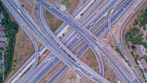 Top down aerial of cars drive across the expressway road in Canada. Cityscape and Highway. Transportation traffic at multilevel high speed road complex in North America.