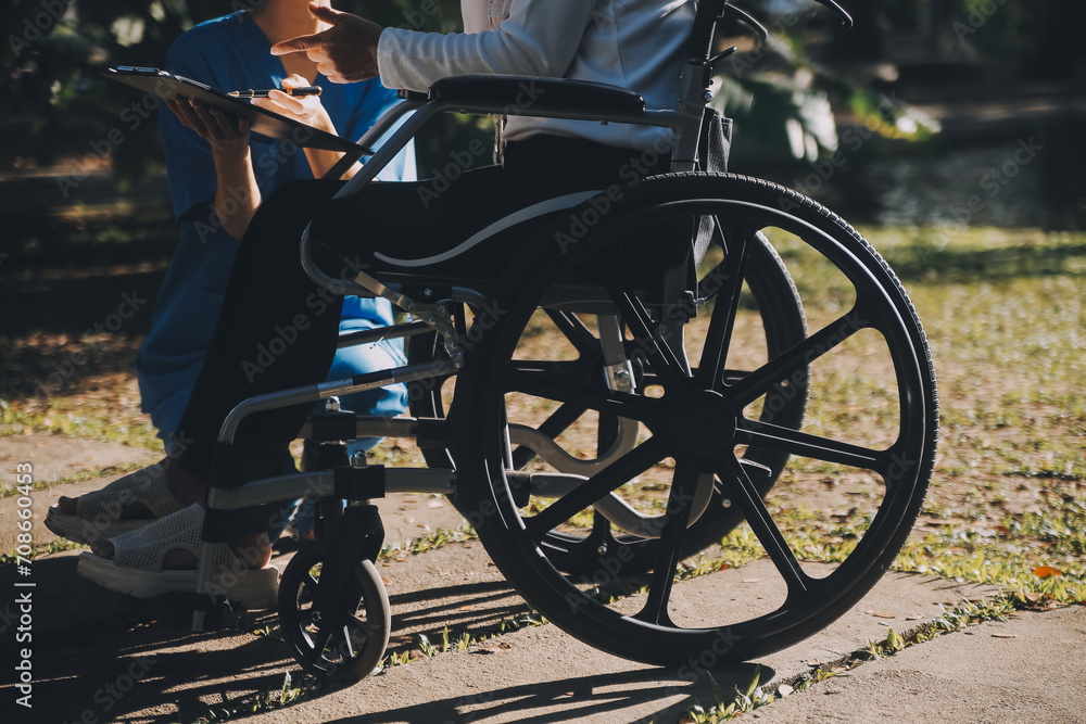 Nursing staff talking to an elderly person sitting in a wheelchair.