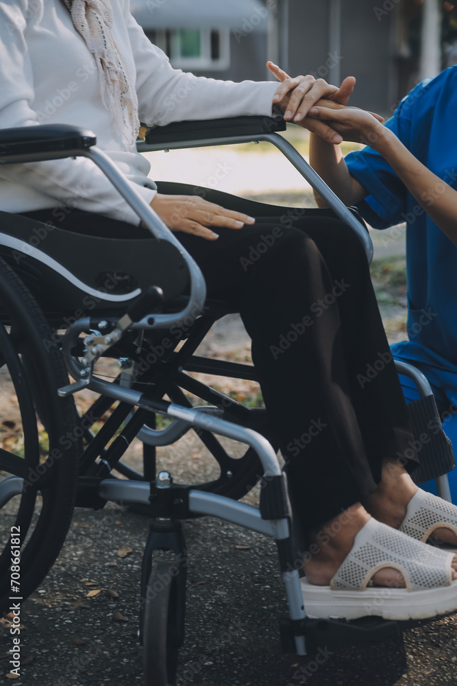 Obraz premium A nurse take care a senior male on wheelchair in his garden at home