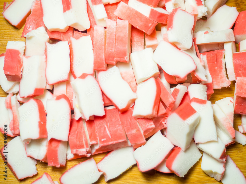 Crab sticks cut into pieces. Cutting with a knife. Ingredient on cutting board. Fish salad ingredient. Ingredient for salad. Crab sticks cut into pieces. Cutting with a knife. Ingredient on cutting board. Fish salad ingredient. Ingredient for salad.