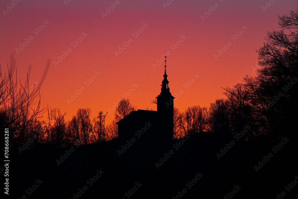 Silhuette of a church in front of a vibrant sunset