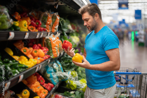 Handsome man with shopping basket with grocery. Man buying groceries in supermarket. Male model in shop. Concept of shopping at supermarket. Shopping with grocery cart at grocery store.