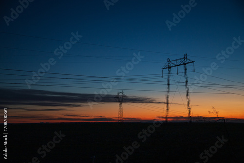Electric poles and lines over farmland at sunset © ralij