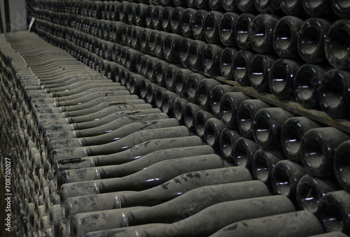 Making traditional champagne. Bottles of sparkling wine, already covered with dust, are stacked in a row. A wine that has been aged for a long time in the bottle. © thekraynov