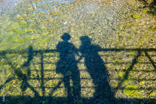 Silhouette of couple travelers tourist enjoy their vacation. Romantic view of two people shapes, man and woman together on bridge of Manitou River near Sandfield Dam, Lake Manitou. Family adventure.