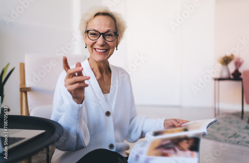 Cheerful senior woman smiling while reading magazine photo