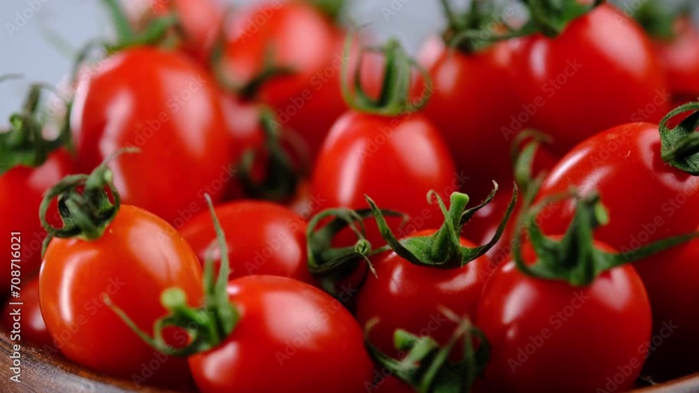 Wet cherry tomatoes lie in a wooden bowl on a white background Wet cherry tomatoes lie in a wooden bowl on a white background