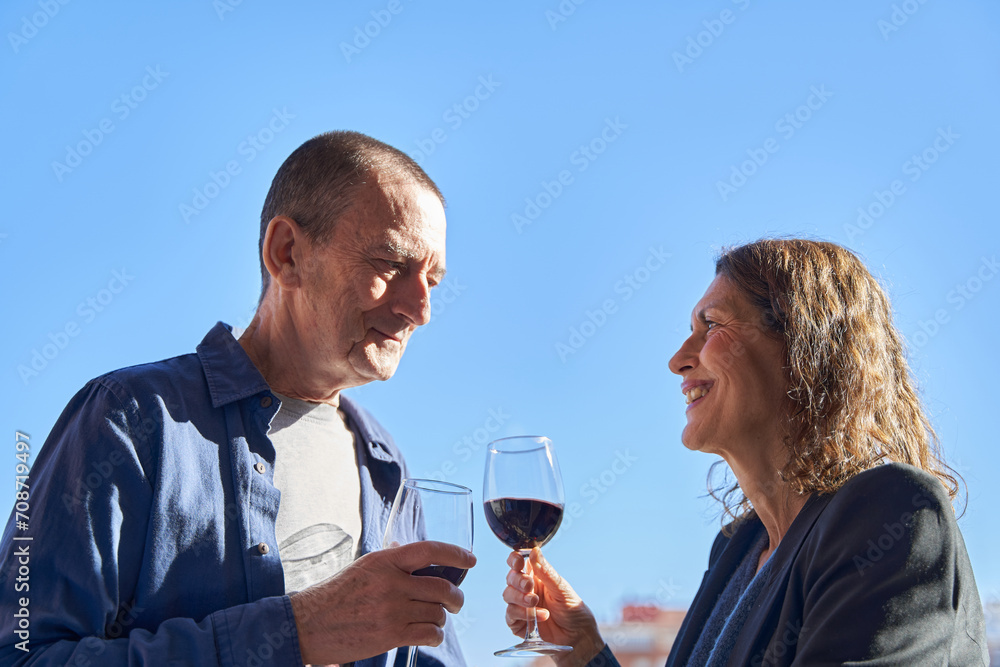 Mature couple on date drinking glass of wine on rooftop on sunny day with copy space Mature couple on date drinking glass of wine on rooftop on sunny day with copy space