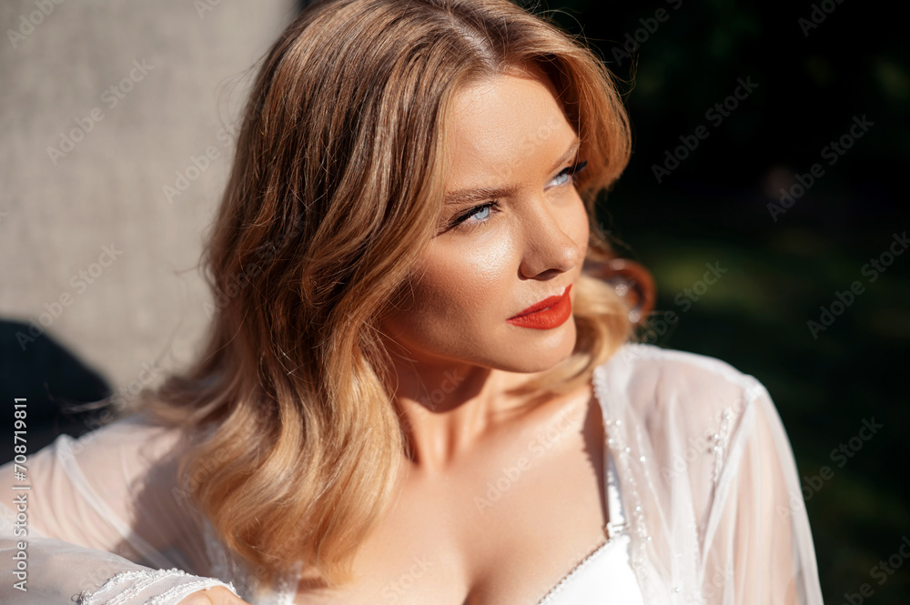 Portrait of attractive young woman with blue eyes and blond hair posing on nature. Stunning bride having wedding makeup and hairstyle. Concept of people, event and celebration.