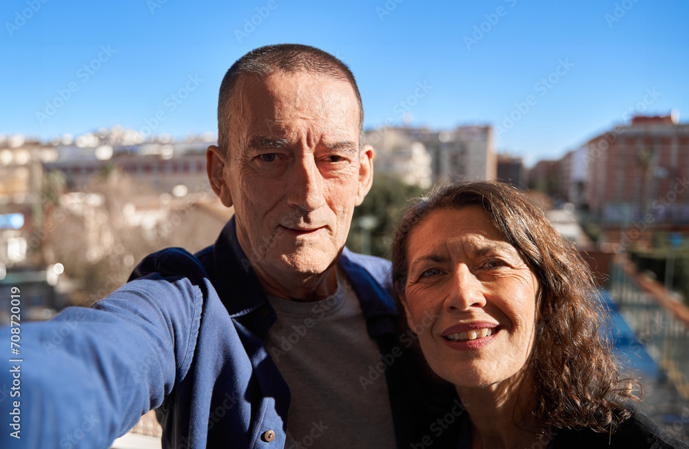 Mature senior couple happy while smiling taking selfie with smartphone on rooftop
