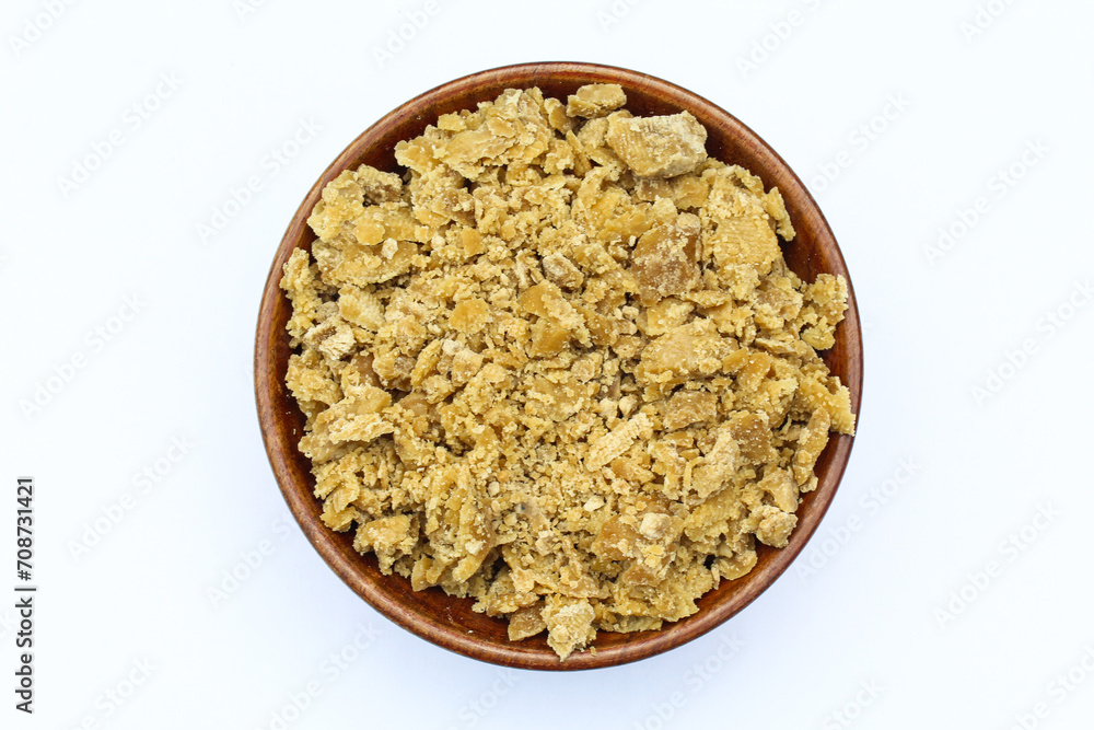 Jaggery in a wooden bowl on white background top view Jaggery in a wooden bowl on white background top view