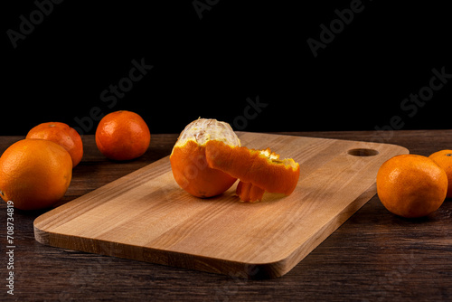 Half peeled orange on a cutting board.