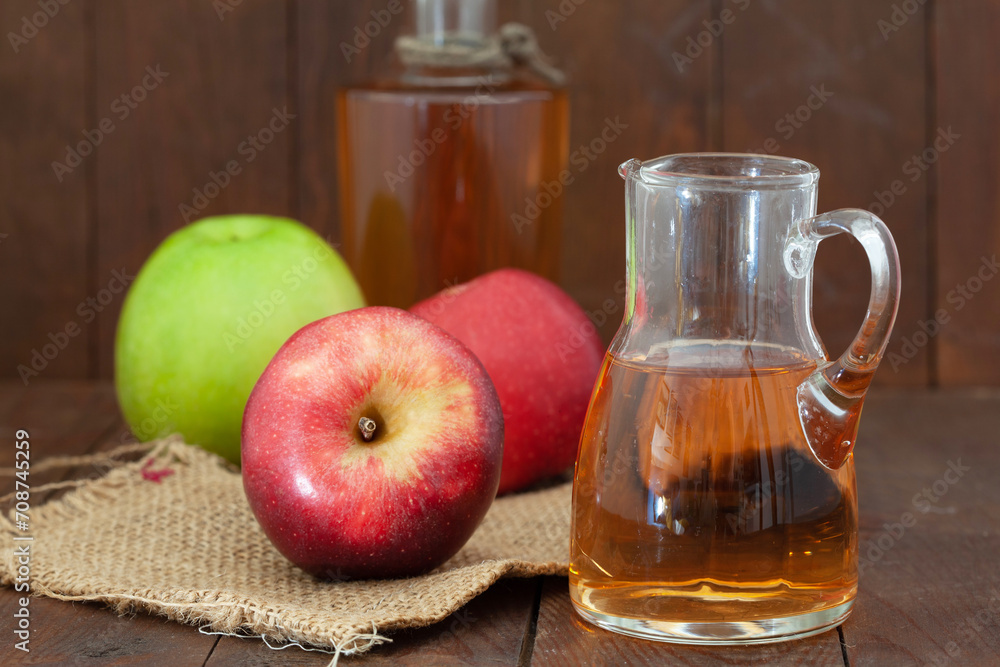 Homemade Apple vinegar in a bottle and a jar with red and green apples on the table. Healthy dressing for a salad. Homemade Apple vinegar in a bottle and a jar with red and green apples on the table. Healthy dressing for a salad.