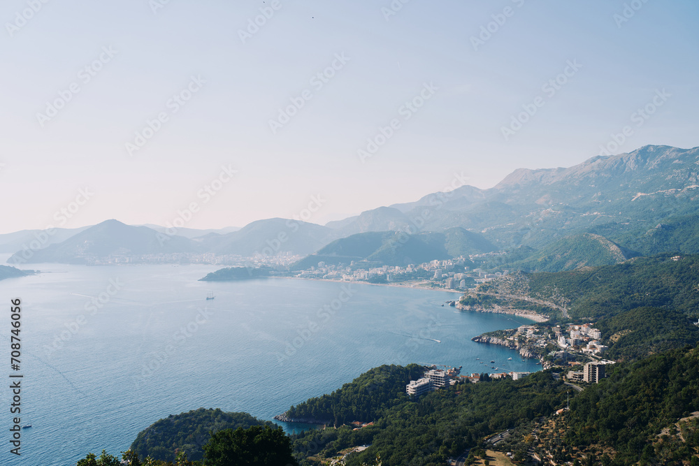 Adriatic Sea hugs the rugged coastline with resort towns at the foot of the mountains. Montenegro. Drone