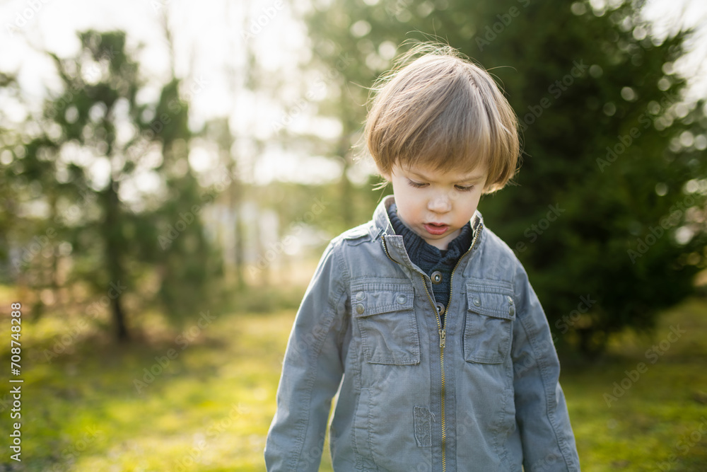 Cute toddler boy playing outdoors on sunny spring day. Child exploring nature. Cute toddler boy playing outdoors on sunny spring day. Child exploring nature.