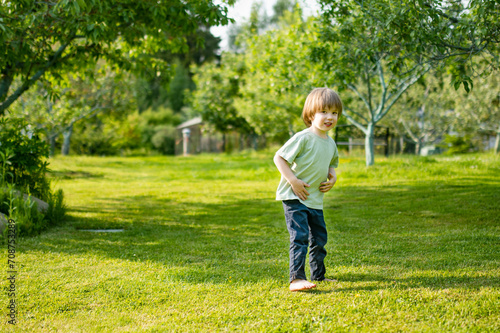 Cute toddler boy playing outdoors on sunny spring day. Child exploring nature. © MNStudio