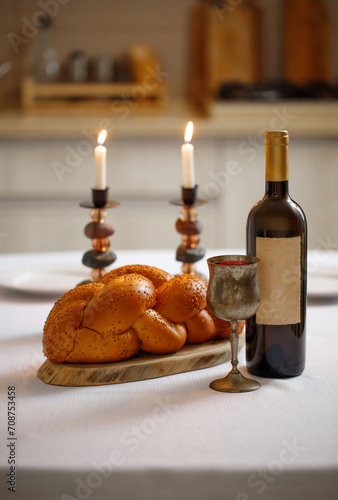 Challah bread, shabbat wine on the kitchen table. Traditional Jewish Shabbat ritual. Shabbat Shalom.