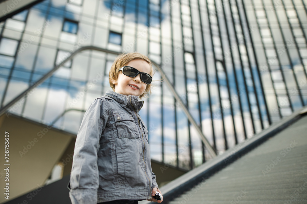 Funny little boy having fun outdoors on sunny spring day. Child in the city. Kid playing in a city park.