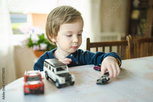 Cute toddler boy playing with toy cars. Small child having fun with toys. Kid spending time in a cozy living room at home.