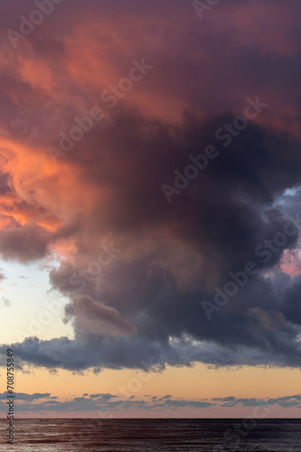 Big fluffy sunset clouds in summer. Orange and purple colors. Golden hour