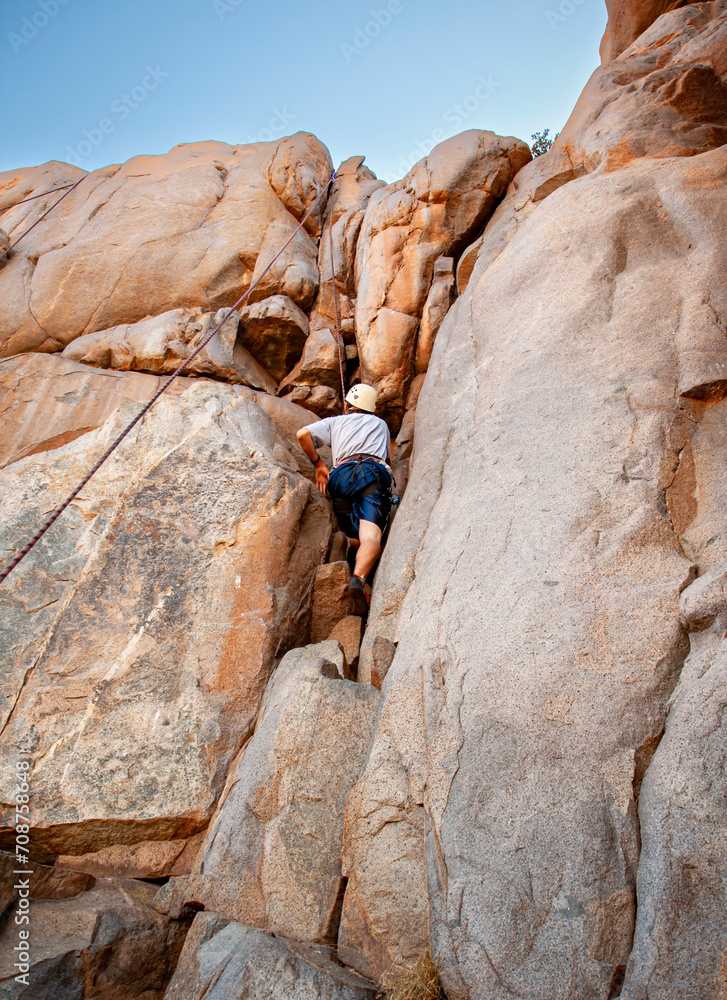 Far shot of a rock climber entering a cravasse on a steep rock face