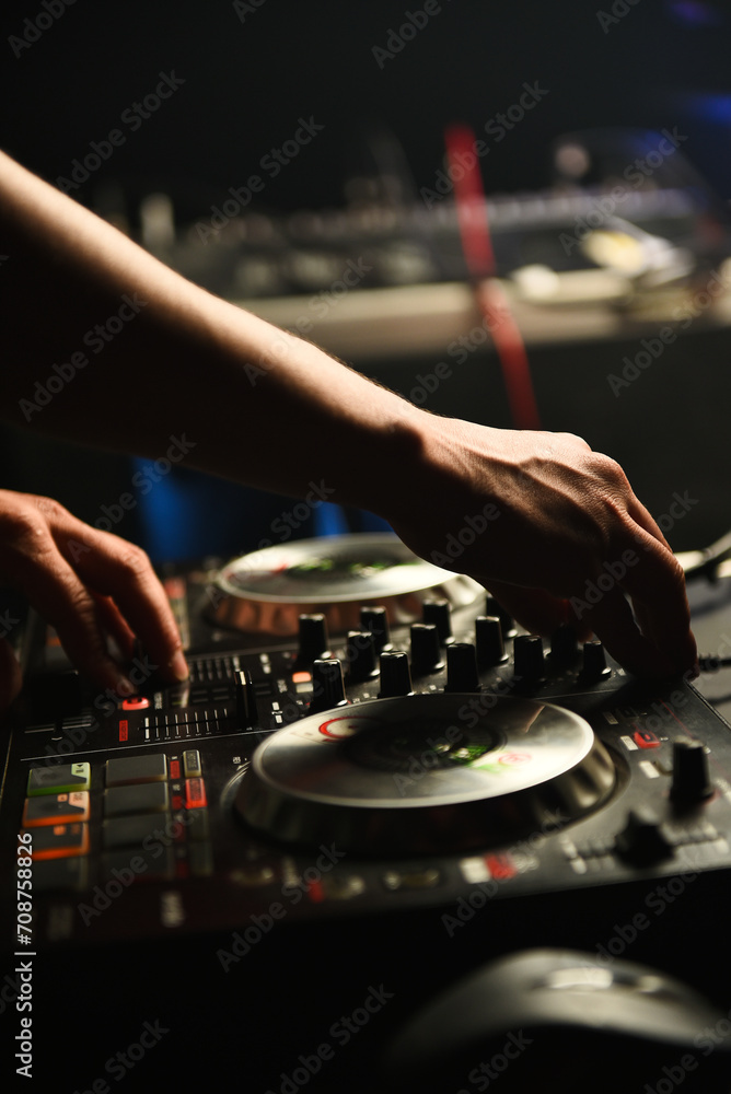 DJ standing at the mixer controller, composing a new mix and making the party in a nightclub nightlife concept. dj concept. party concept. bokeh background. DJ standing at the mixer controller, composing a new mix and making the party in a nightclub nightlife concept. dj concept. party concept. bokeh background.