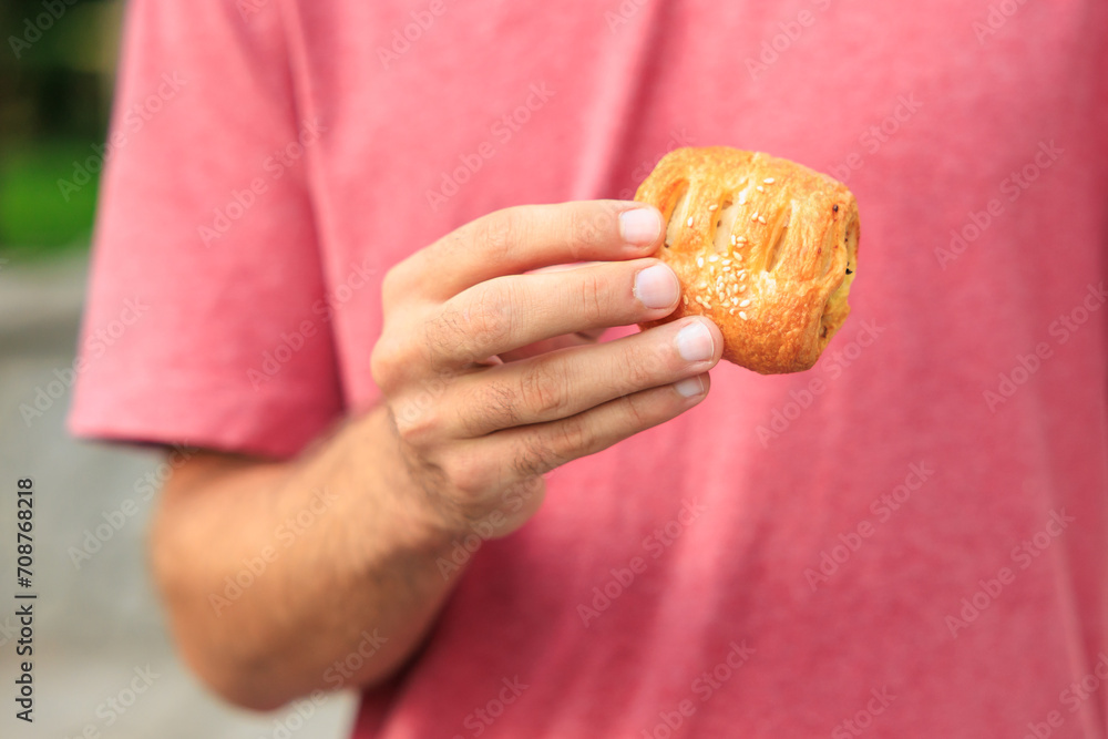 A guy's hand holds a mini puff pastry with cheese, snack and fast food concept. Selective focus on hands A guy's hand holds a mini puff pastry with cheese, snack and fast food concept. Selective focus on hands