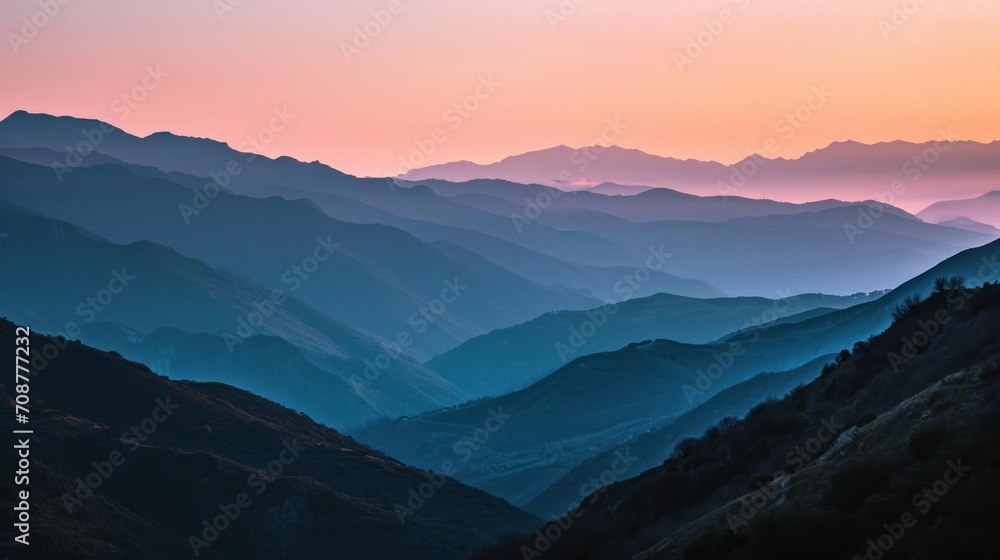  a view of a mountain range at sunset from the top of a mountain in the distance is a pink and blue sky with a line of mountains in the foreground.