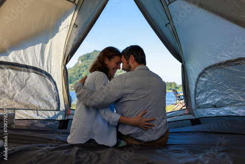 caucasian couple sitting inside a tent on a camping trip,