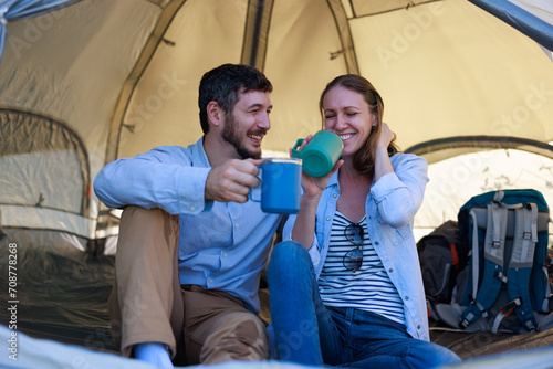 couple drink coffee and talking while they sit inside their tent on a camping trip © SHUTTER DIN