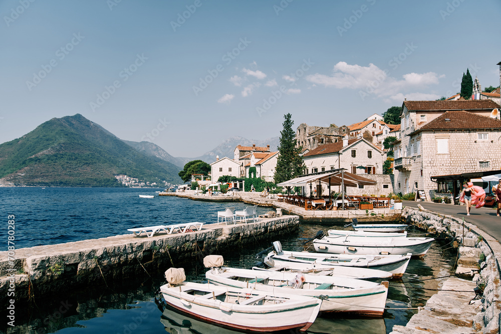 Row of white fishing boats is moored along the Perast promenade. Montenegro