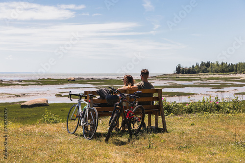 couple with bikes in the park looking at the river sitting on a bench