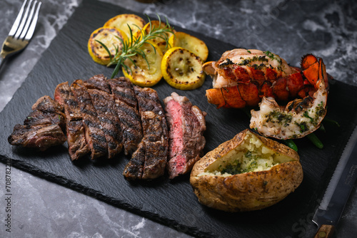 surf and turf, ribeye steak and lobster tail on black marble background photo
